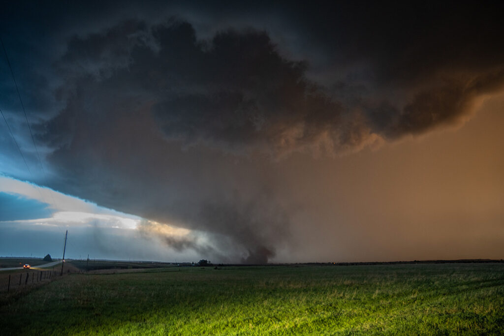 A truck is parked in the foreground, with a large storm system in the background.